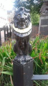 About: black Lion statuette with gold mane topping fence post in summer